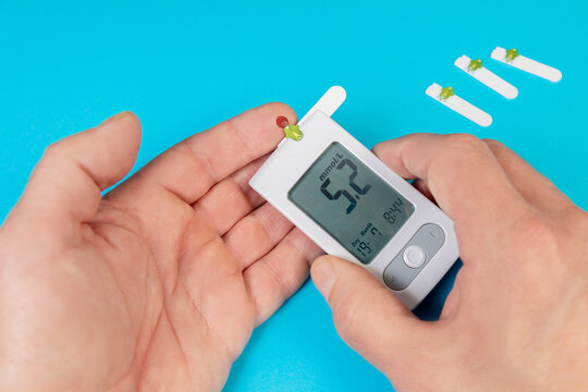 Using a glucometer to check blood glucose levels at home for diabetes monitoring - Powered by Adobe