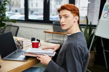 Young red haired man working diligently in a modern office environment