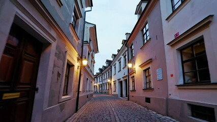 Twilight walk through quaint cobbled alleyway with antique street lamps