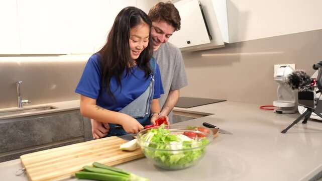 Multiethnic couple preparing a healthy salad together in their modern kitchen, sharing a moment of love and complicity