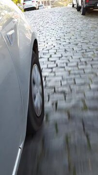 imagem em baixo angulo de roda de carro rodando em rua de paralelep&iacute;pedo 