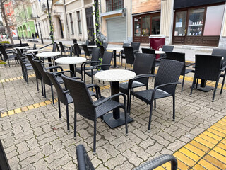 Empty street cafe tables and chairs in a quiet urban setting. City routine, leisure, and public...