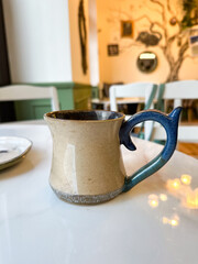 Artisan coffee mug on white marble table in cozy cafe. Calm, presence, and the simple beauty of daily rituals and handmade design
