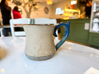Artisan coffee mug on white marble table in cozy cafe. Calm, presence, and the simple beauty of daily rituals and handmade design