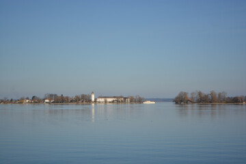 Fototapeta premium Fraueninsel, Frauenchiemsee on lake Chiemsee in the morning sunrise with boat, Sailboat, church, monastery. Bavaria, Bayern, Germany
