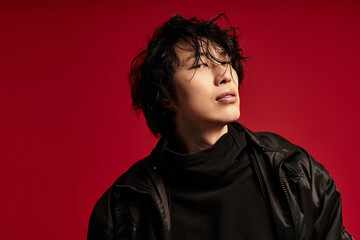 A stylish moment asian man poses against a vibrant red backdrop