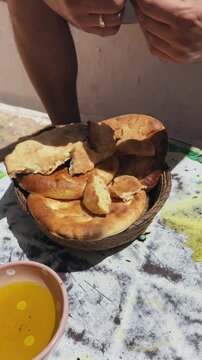 The hands of a man breaking freshly baked bread served with olive oil at a Sahara Berber village in Tunisia
