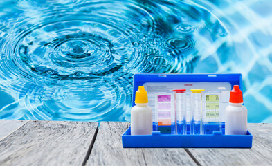 Water tester test kit on wooden table over blurred resort swimming pool background, swimming pool...