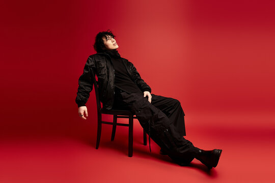 Urban vogue asian man exudes confidence in studio against a vivid red backdrop