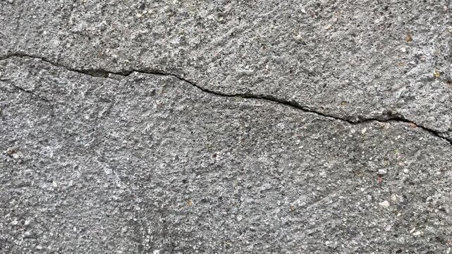 Cracked grey concrete wall, closeup