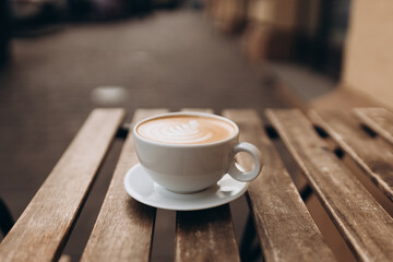 Cup of coffee on the wooden table with latte art. Street coffee, top view. Coffee in a white cup with latte art.