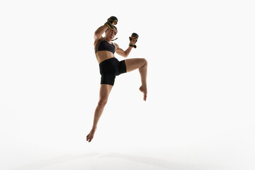 Young woman, fighter jumping with raised fists wearing boxing gloves isolated on white background. Concept of kickboxing, action, energy, combat sport, competition, strength, motion, confidence.