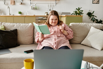 Young woman with Down syndrome enjoys cozy time at home while reading and smiling with confidence
