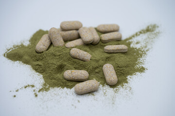 Moringa powder and organic capsules on white background