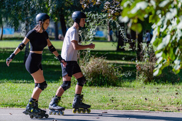 Young couple enjoys rollerblading on a sunny summer day in a lush park. The pair glides through scenic trails, embracing an active lifestyle and sharing a joyful outdoor experience. © Microgen