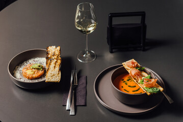 Salmorejo soup with prosciutto and pesto, paired with tartare on a parmesan-dusted plate. Stylish dark composition, moody lighting, elegant plating, and a refined gourmet dining experience.