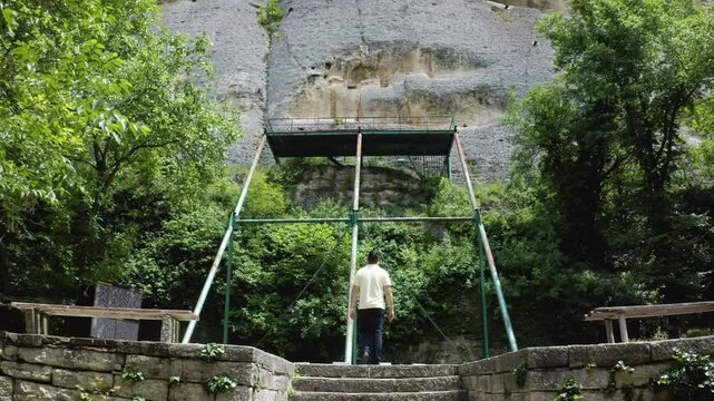 Approaching drone shot of a tourist walking towards a tourist spot of the Madara Rider, Madara Horseman, or more known locally as Madarski Konnik in the Madara Plateau near Shumen in Bulgaria.