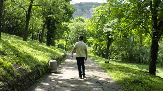 Walking on a cobble-stoned pathway, a tourist is looking around the green surroundings as he walks towards the tourist spot of Madara Horseman or locally known as Madarski Konnik in Bulgaria.