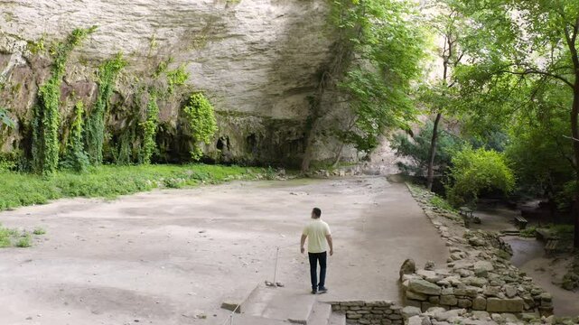A lone tourist walking in front of the rock wall of the Madara Plateau near Shumen, where the Madara Rider or commonly known as Madarski Konnik in Bulgaria.