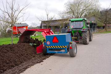 Tractor pulling compost turner and mixing heap of compost at Swiss City of Zürich on a cloudy...