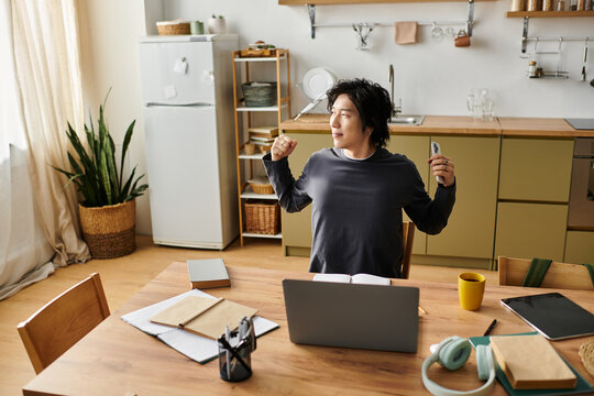 Young asian man studies online from home while stretching in modern kitchen space