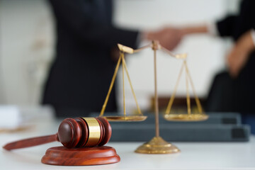 Authority and Legal Decisions. A gavel and scales representing legal authority while two professionals shake hands after finalizing their agreement.