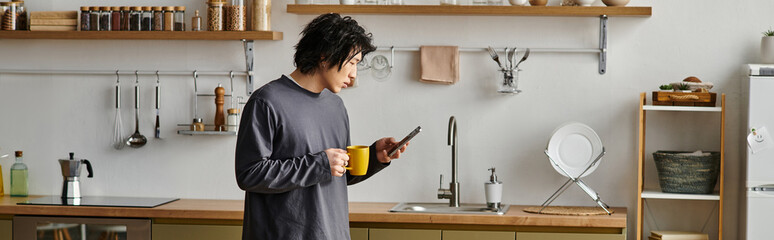 Young asian student engaged in online learning at home while sipping coffee