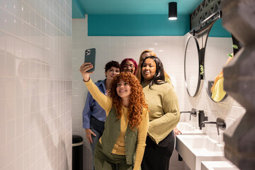 Group of diverse female friends taking a selfie in a public restroom