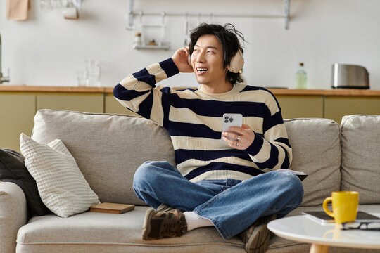 Young asian man enjoying music at home in a modern apartment with cozy vibes