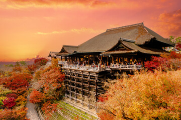 Obraz premium Kiyomizu-dera's iconic wooden stage, Japan, amidst autumn's fiery foliage, glows under a dramatic sunset. Ancient architecture blends with nature's vibrant hues.