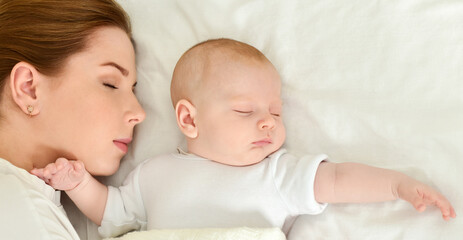Young mother and her baby, sleeping in bed. Mother and baby. Happy family.