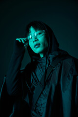 Young stylish asian man wearing glasses and a hood enjoying a fashion moment in cool lighting