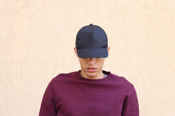 Man in stylish baseball cap near beige wall. Mockup for design