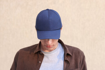 Man in stylish baseball cap near beige wall. Mockup for design