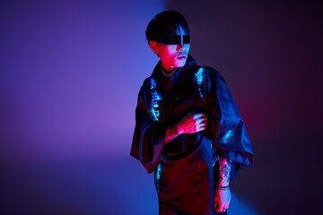 Stylish young asian man showcases modern fashion with vibrant lighting in a creative studio setup