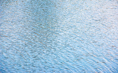 Water surface at sunset, ripples of river or ocean with small waves, close-up. Natural background. Abstract background, texture.