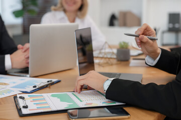 Coworkers working together at wooden table in office, closeup