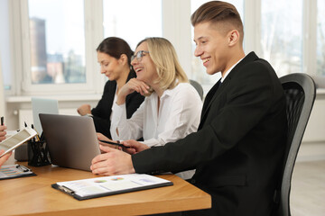 Coworkers with laptop working together at wooden table in office