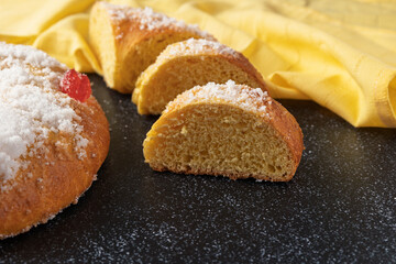 Sliced roscón de reyes showing its fluffy texture on dark background