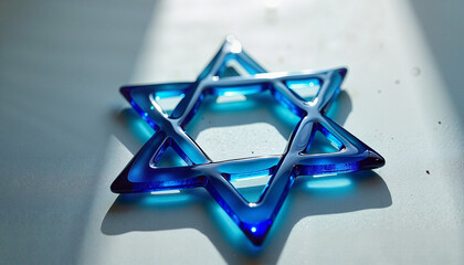 Blue glass Star of David ornament reflecting light on a white surface