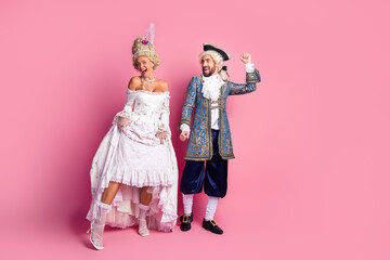 Elegant Couple in Vintage Costumes Posing Against a Pink Background