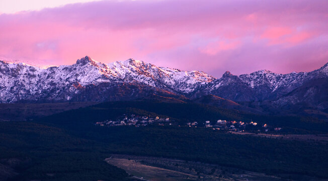 Dramatic purple sunset above snowy rugged summits of Los Cumbres Verdes, part of the Sierra Nevada, viewed from Granada, Andalucia, Spain