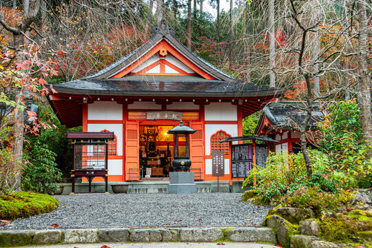 A vibrant red shrine surrounded by greenery and autumn colors, located near Sanzen-in Temple in Ohara, Kyoto, Honshu
