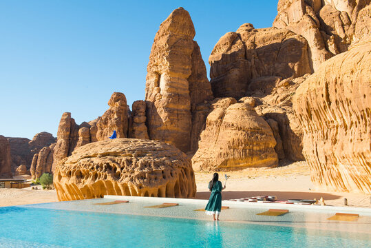 Woman by swimming pool, surrounded by sandstone rock structures, Our Habitas AlUla, oasis in the Ashar Valley, Medina Province