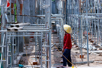 Vietnamese worker setting up scaffolding on a construction site, Tan Chau