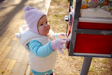 Child Enjoying a Colorful Gumball Machine Near a Park on a Sunny Day in Early Spring