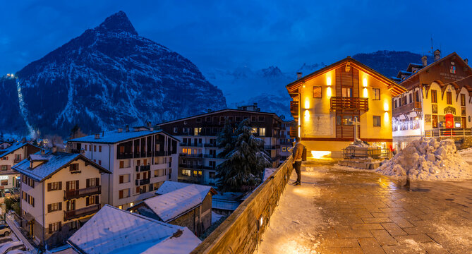 View of snow covered rooftops with mountainous background and Piazza Abbe Henry at dusk, Courmayeur, Aosta Valley