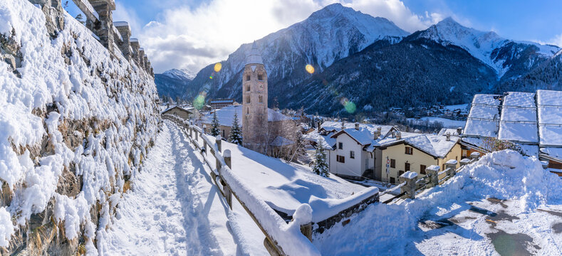 View of snow covered mountains, rooftops and Church of Saint Pantalon in Courmayeur in winter, Courmayeur, Aosta Valley, Italian Alps