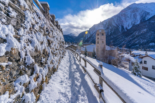 View of snow covered mountains, rooftops and Church of Saint Pantalon in Courmayeur in winter, Courmayeur, Aosta Valley, Italian Alps