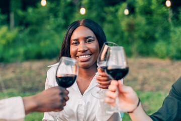 Friends toasting with red wine glasses at outdoor party
